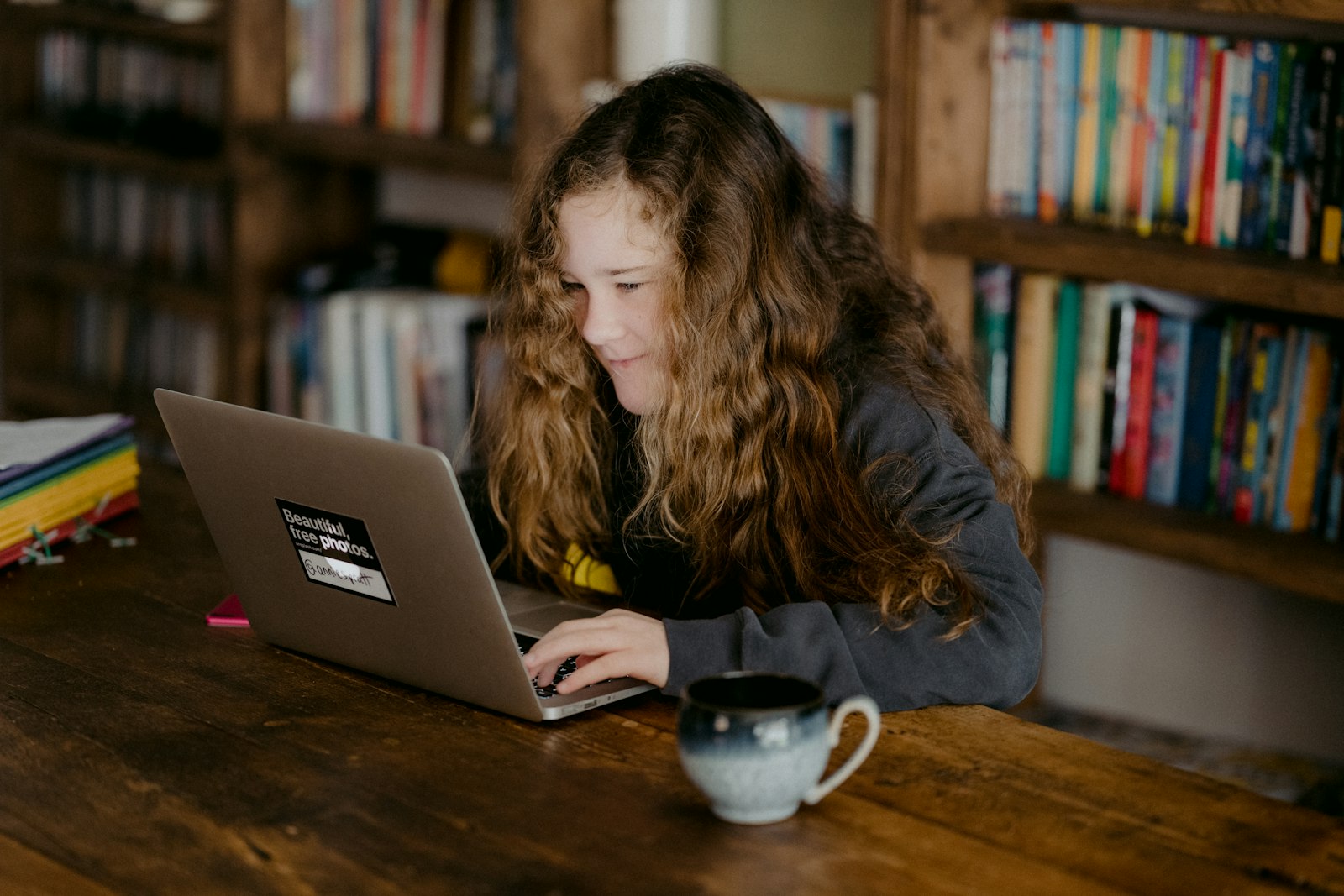 A young student working on a laptop at a wooden table